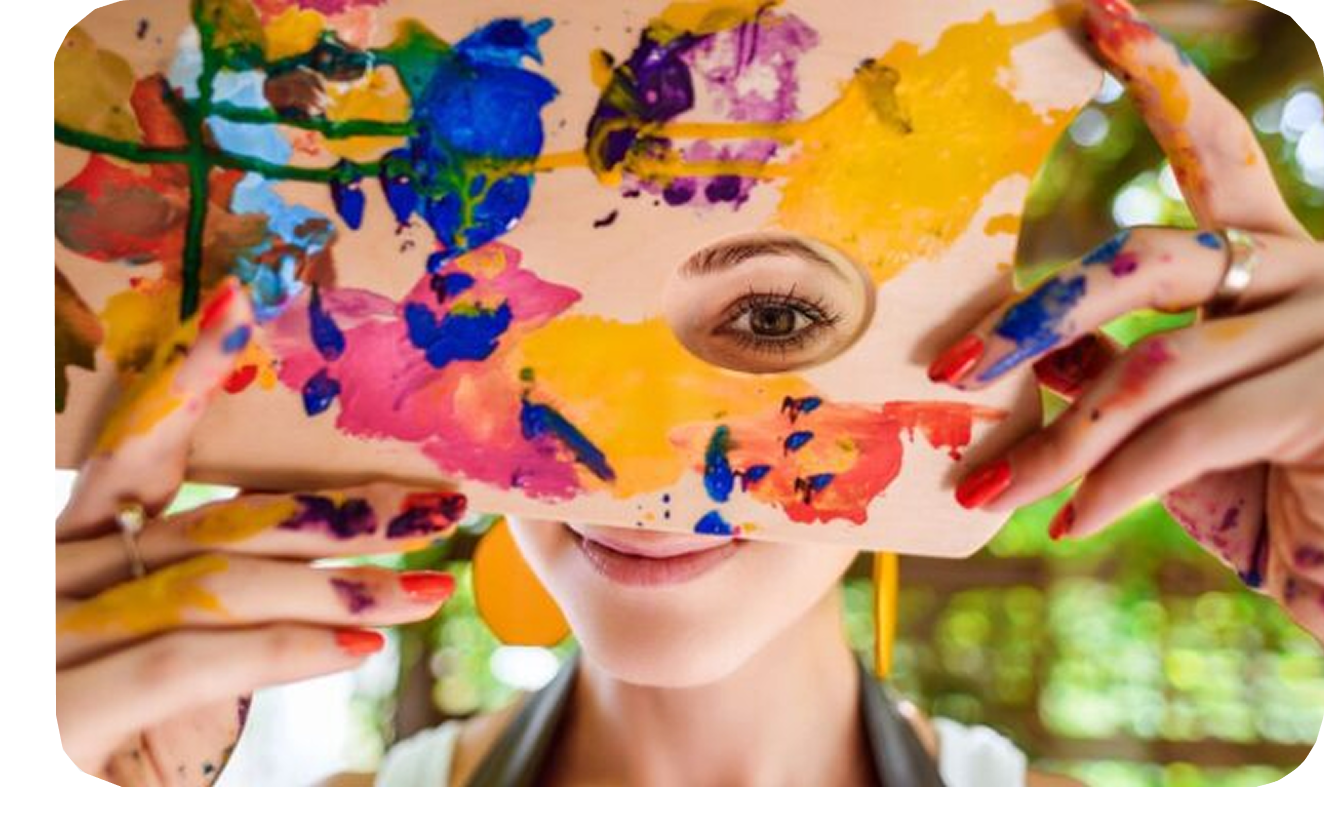 Group-1321316424 A woman holding up a painting with paint on it.